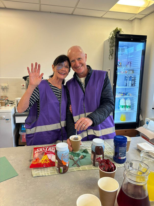 Two voluntneers serving and waving at the autumn fayre