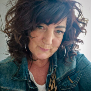 Sue Slade wears a denim jacket and hoop earrings, photographed by Bristol Charities.